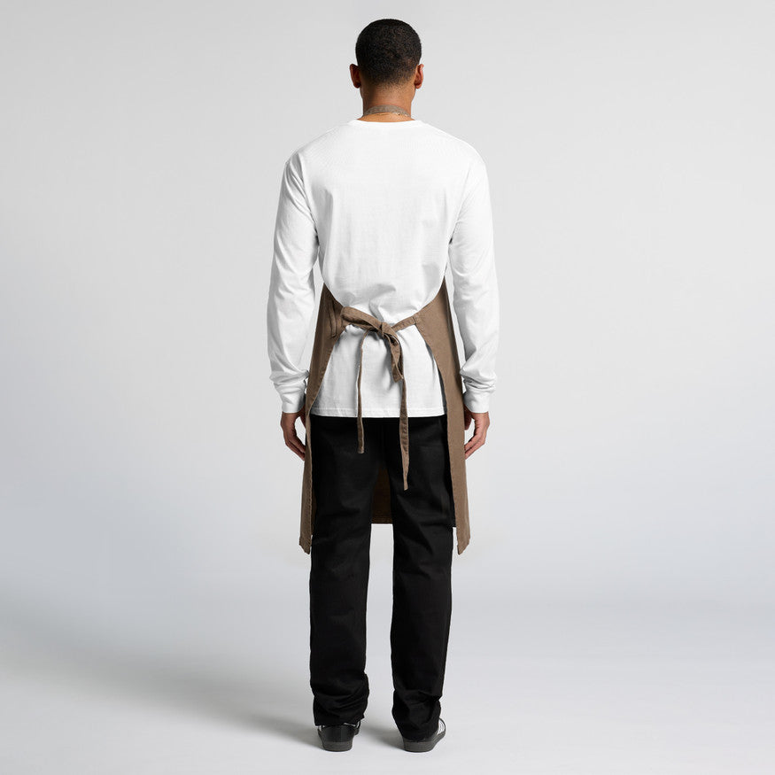 A person in a professional hospitality uniform featuring a white shirt, black pants, and a blank brown apron, optimized for custom Christchurch business branding using embroidery or Supacolor transfers.