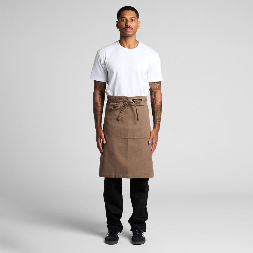 A male model wearing a premium brown bib apron over a plain white crewneck shirt, suitable for custom embroidery or Supacolor branding for Christchurch hospitality or trade uniforms.