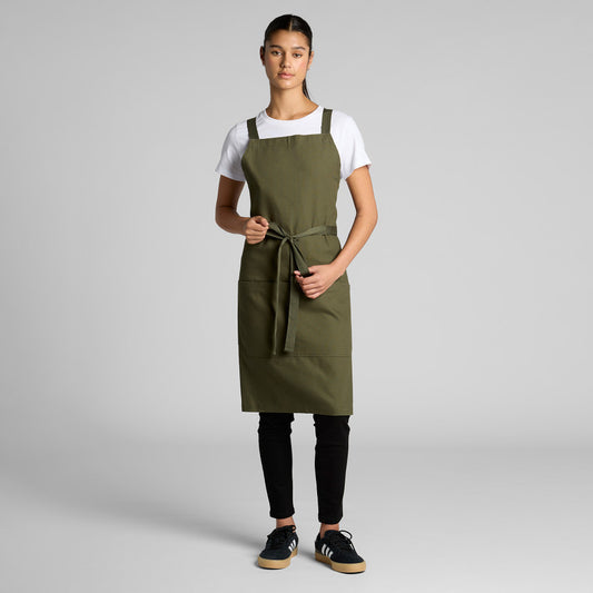 Female model wearing a durable green bib apron, an ideal blank apparel choice for Christchurch cafes, florists, or garden centers seeking custom onsite embroidery or Supacolor branding.