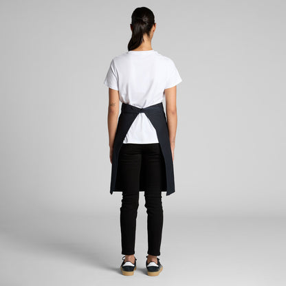Person wearing a white t-shirt and black apron over jeans on a plain background