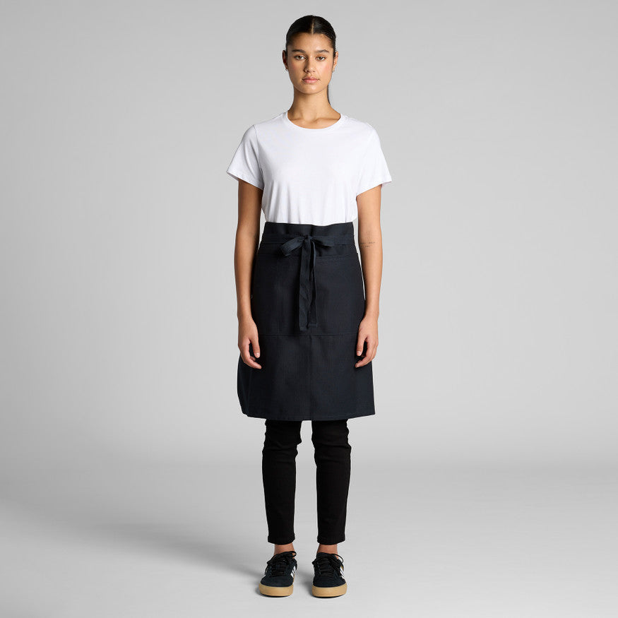 Person wearing a black apron over a white shirt on a gray background