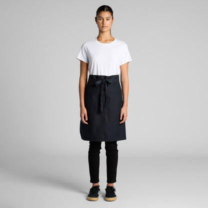 Person wearing a black apron over a white shirt on a gray background