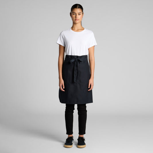 Person wearing a black apron over a white shirt on a gray background
