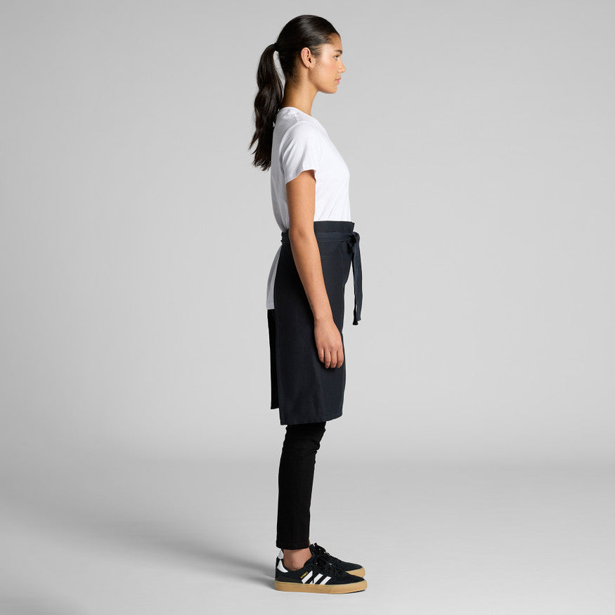 Person wearing a black apron over a white shirt on a gray background