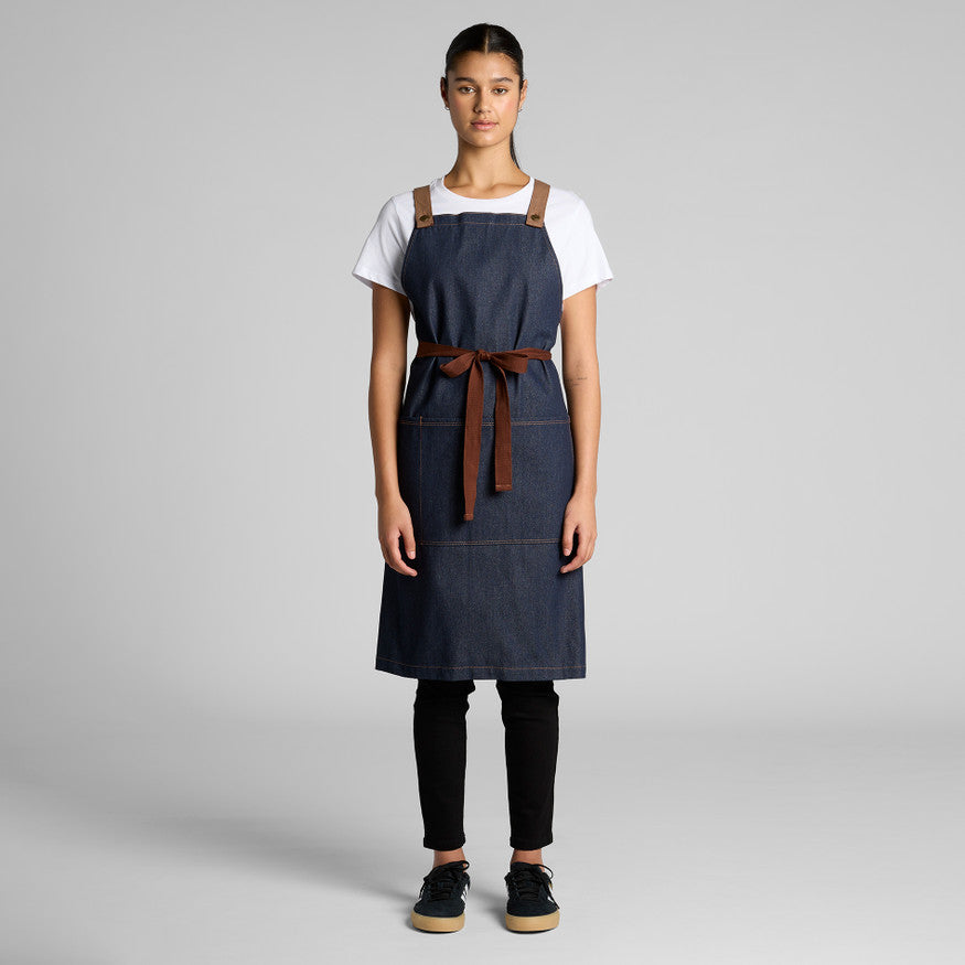Person wearing a blue apron with a brown strap on a gray background