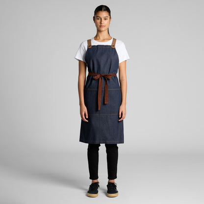 Person wearing a blue apron with a brown strap on a gray background