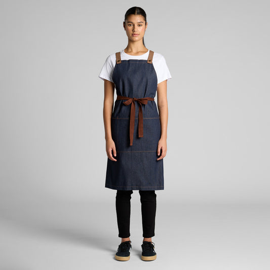 Person wearing a blue apron with a brown strap on a gray background