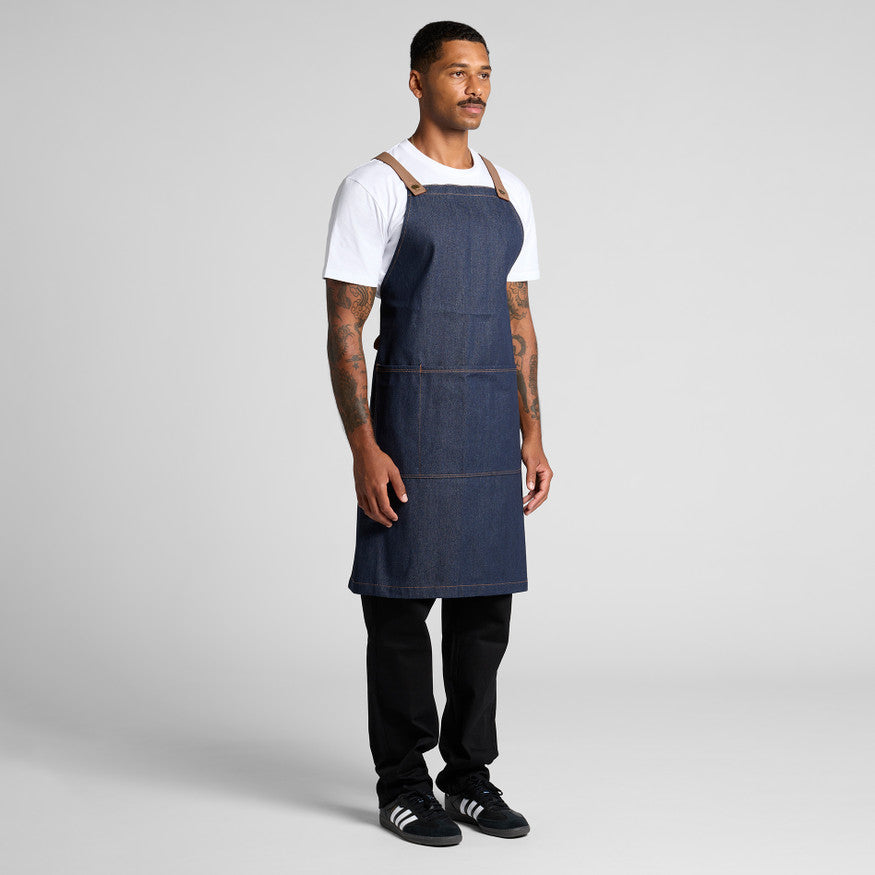 Man wearing a blue apron over a white shirt on a gray background