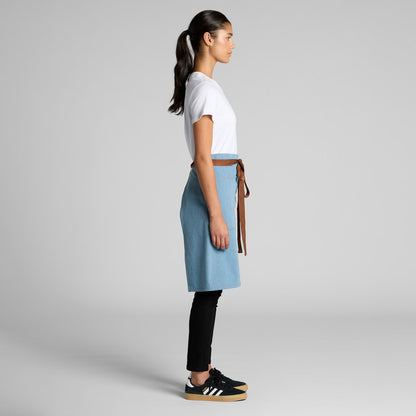 Woman wearing a light blue skirt with a brown belt on a gray background