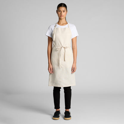 Person wearing a beige apron over a white shirt and black pants on a gray background