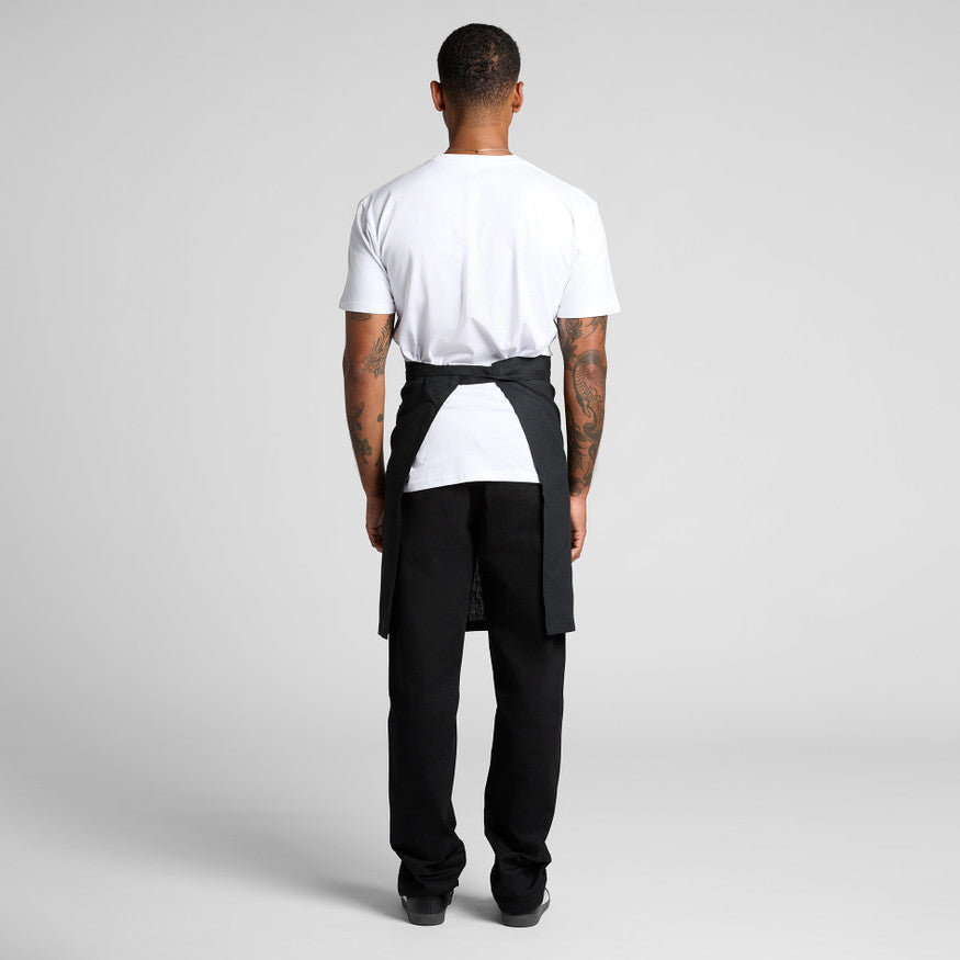 Person wearing a black apron over a white shirt on a gray background