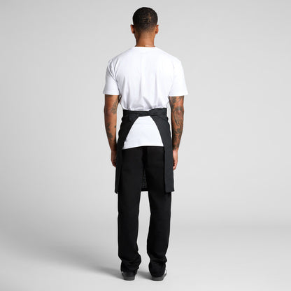 Person wearing a black apron over a white shirt on a gray background
