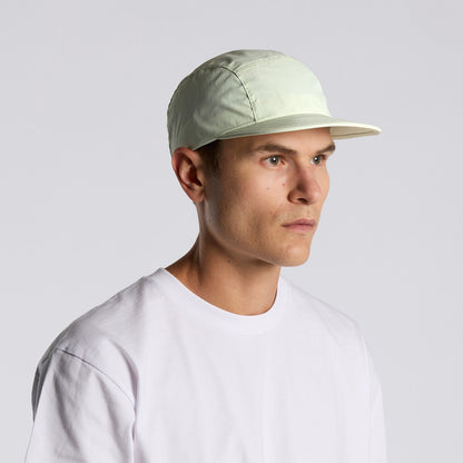 Man wearing a light-colored cap and white t-shirt against a plain background