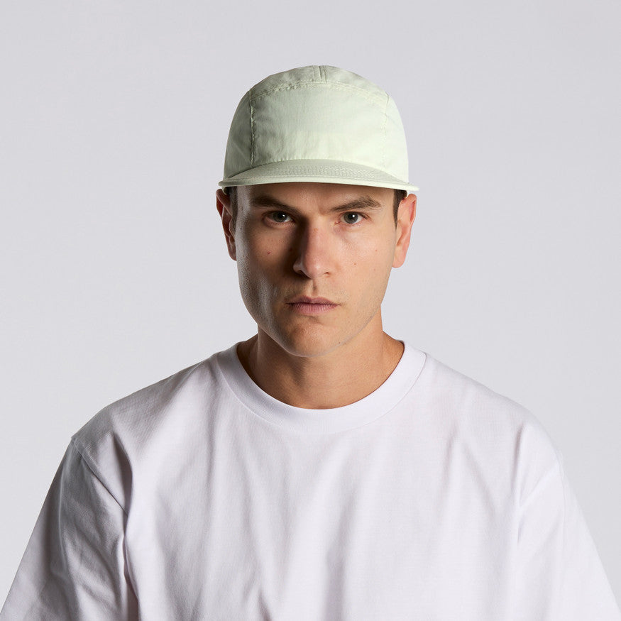 Man wearing a light-colored cap and white t-shirt against a plain background