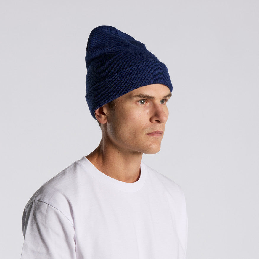 Man wearing a navy blue beanie and white shirt on a light gray background