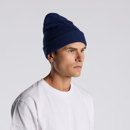 Man wearing a navy blue beanie and white shirt on a light gray background