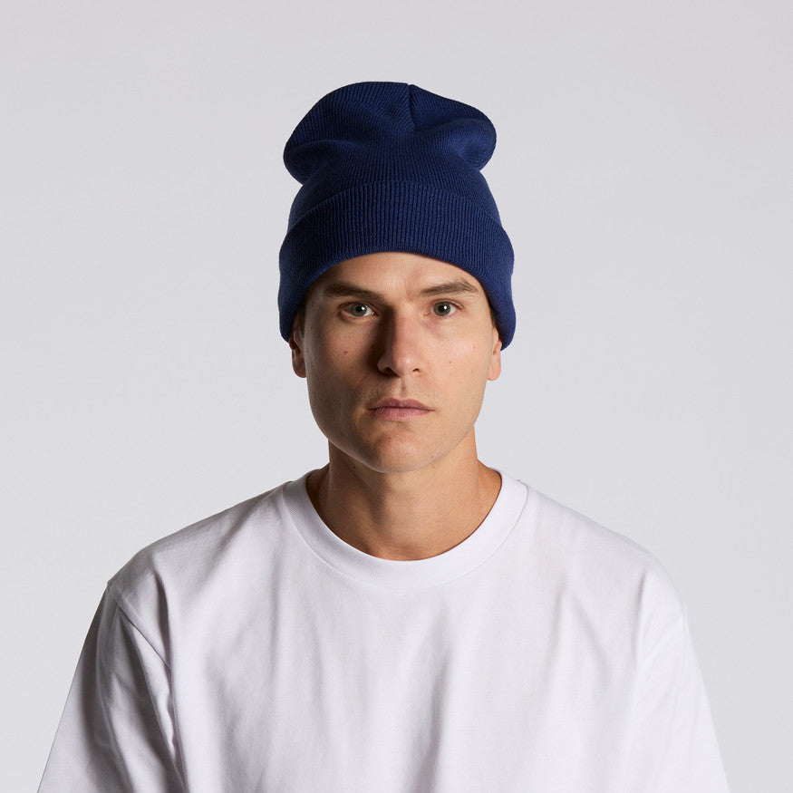 Man wearing a navy blue beanie and white shirt against a light gray background