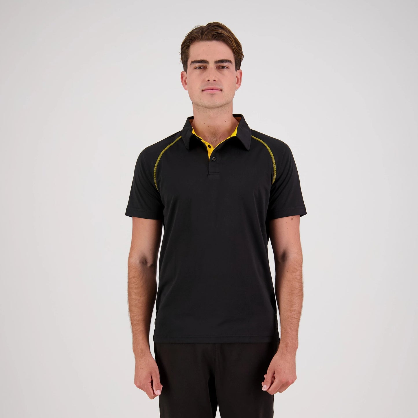 Man wearing a black polo shirt with yellow accents on a white background